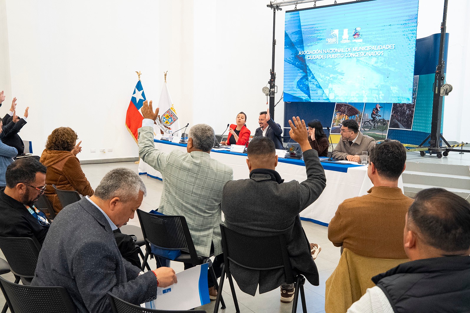 Alcaldes levantan la mano para votar durante la asamblea de la ANCPCH en Coquimbo